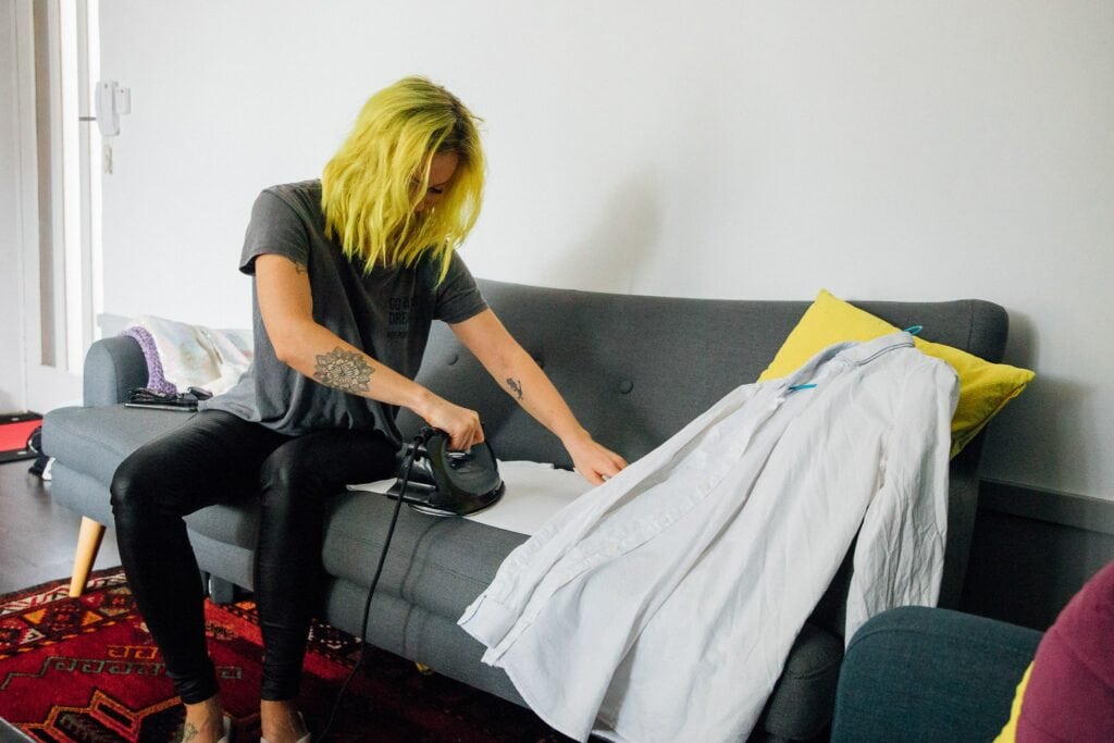 Elopement photography of a rock n roll, quirky bride ironing her fiancé's shirt on the couch in Cape Town, South Africa
