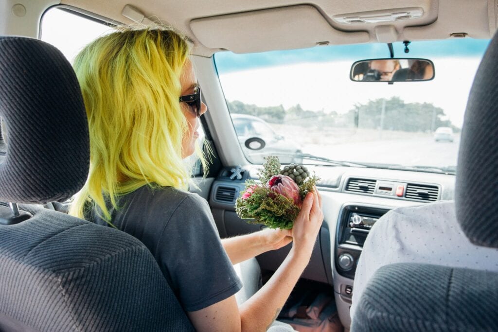 Elopement photography of a rock n roll, quirky bride arranging her bouquet of flowers in the car in Cape Town, South Africa