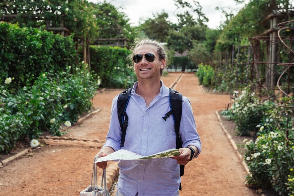 Elopement photography of a quirky best man holding a map in a garden in Cape Town, South Africa